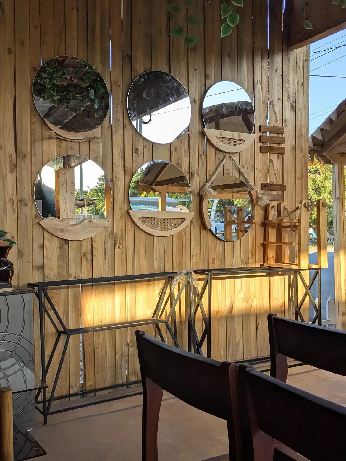 Round mirrors hung in a grid on a timber wall above a metal console table.